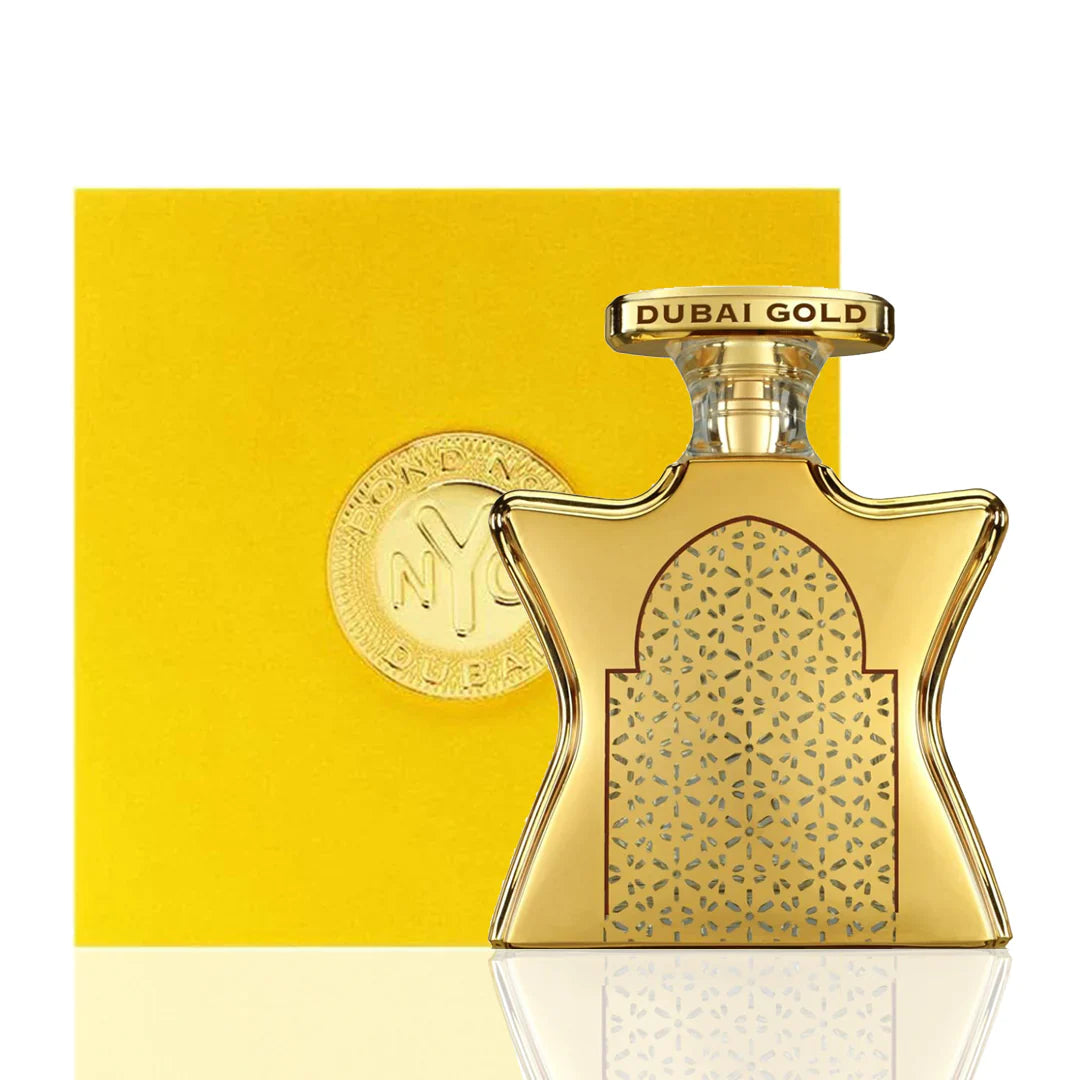 A bottle of Bond No 9 Dubai Gold 3.3 Edp L with a gold-colored label and cap, presented against a yellow background.