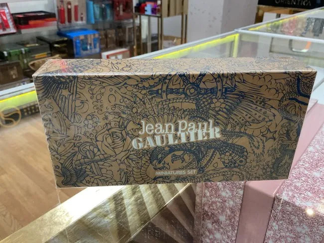 Jean Paul Gaultier product packaging on a reflective surface with a blurred background