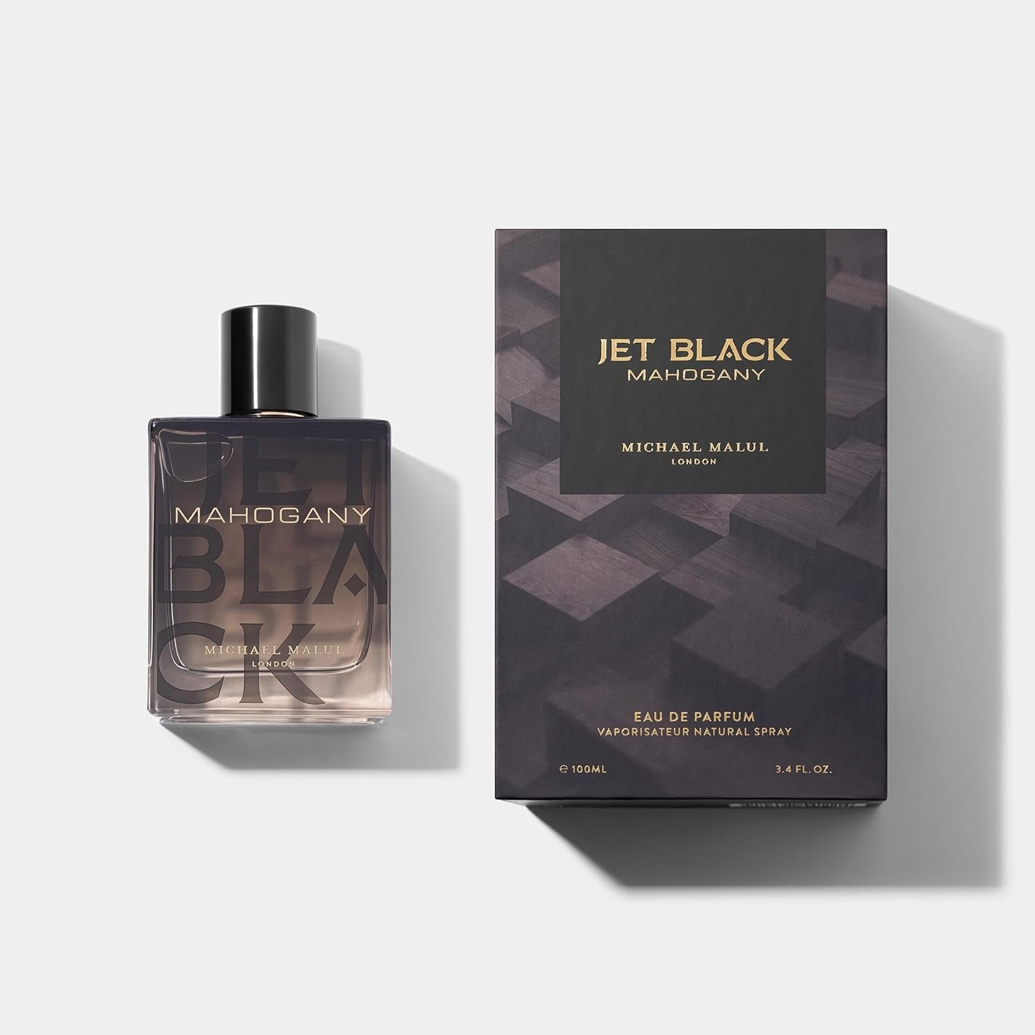 Perfume bottle and packaging of 'Jet Black Mahogany' by Michael Malul on a light gray background